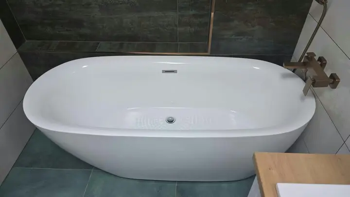 Cadă ovală albă într-o baie cu gresie închisă la culoare