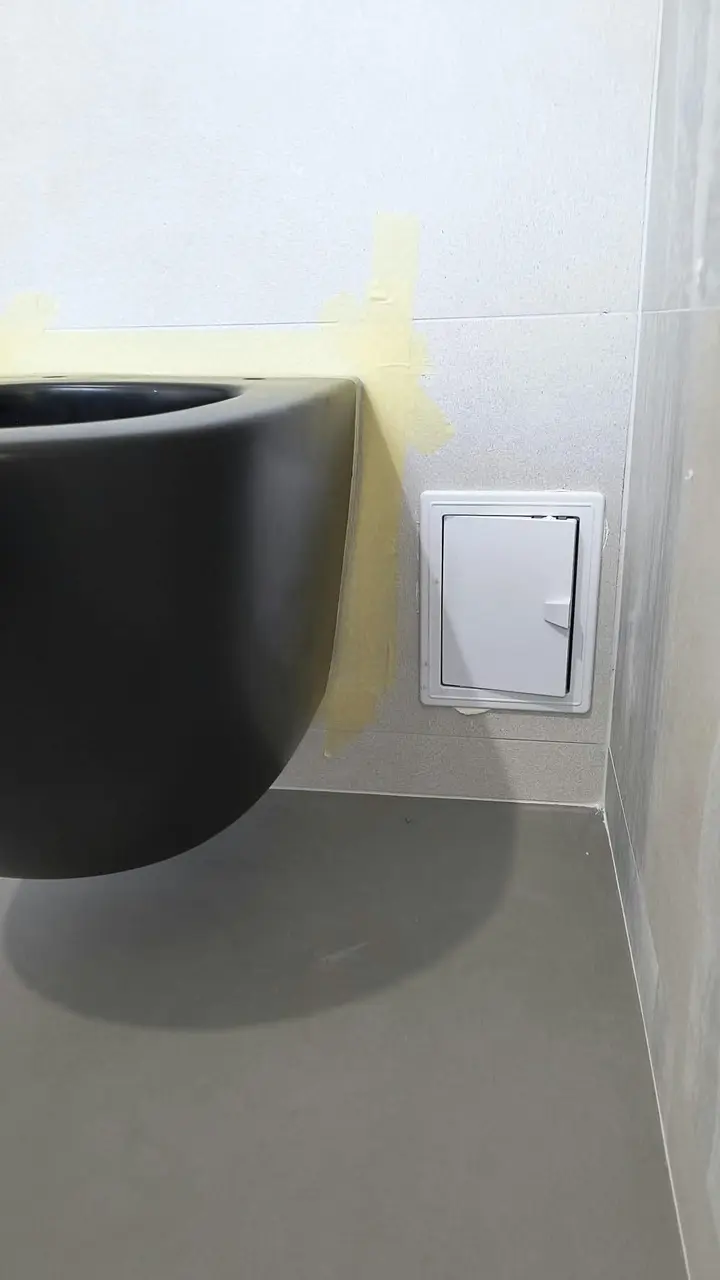Vas WC suspendat negru, cu un capac de vizitare pe peretele alăturat